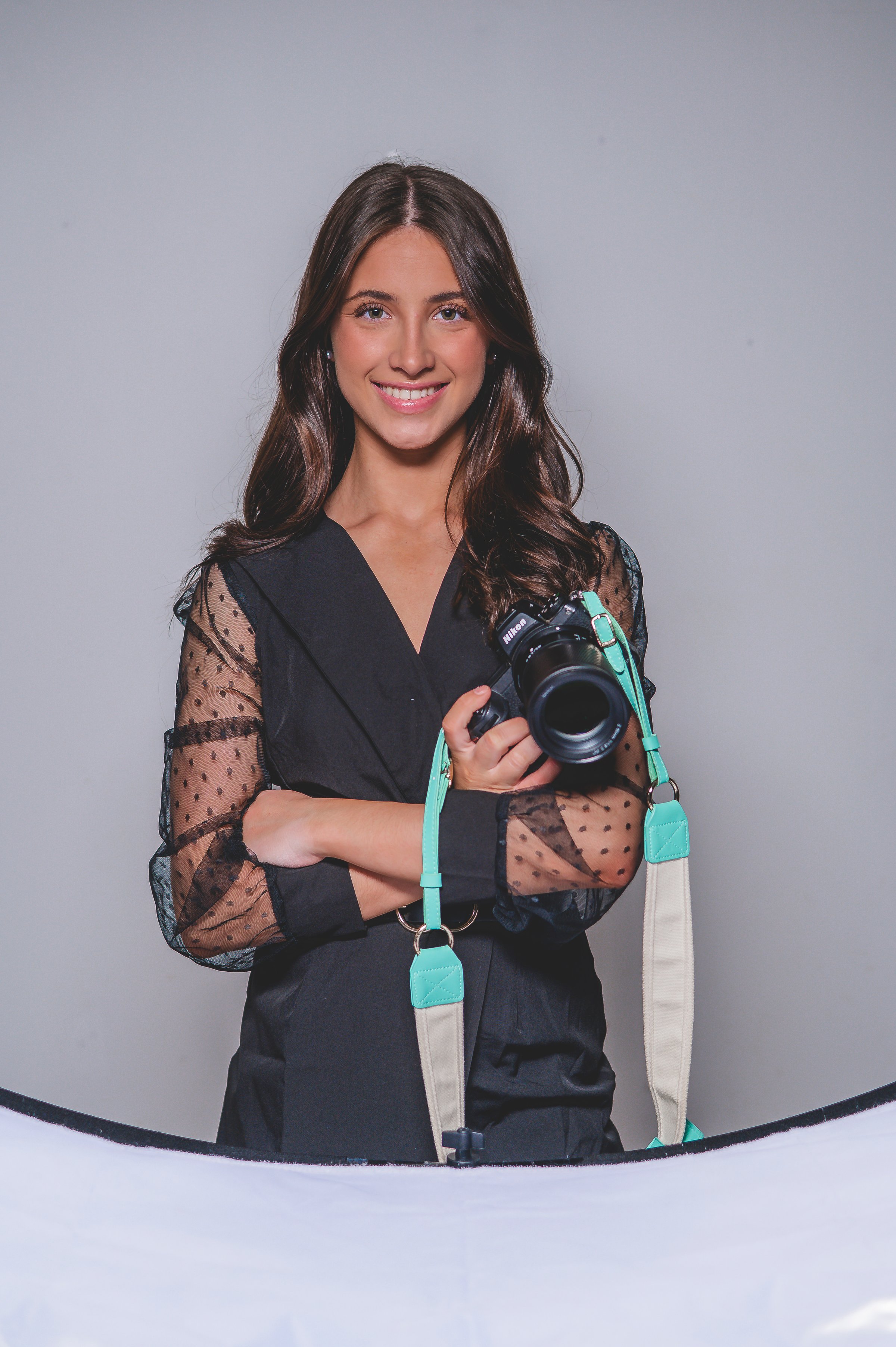 Kennedy, photographer behind Kaptured by Kennedy, holding her camera in studio