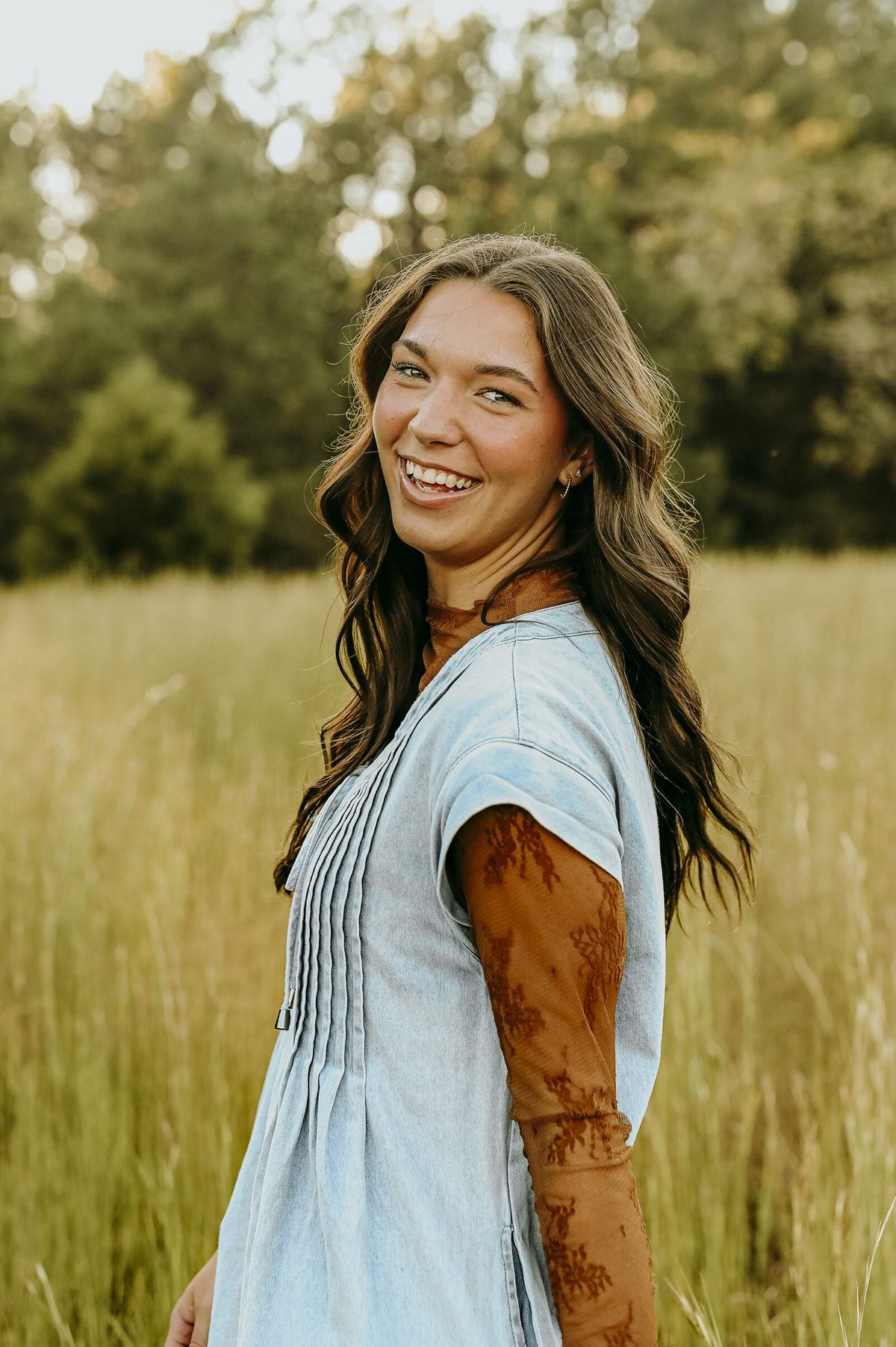 Senior portrait smiling over her shoulder in a summer field